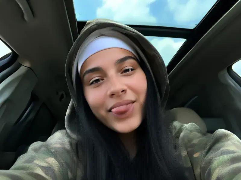 Real FLUX.2 Klein 9B generation: Candid iPhone front camera selfie of a young woman sitting inside a car with a panoramic s