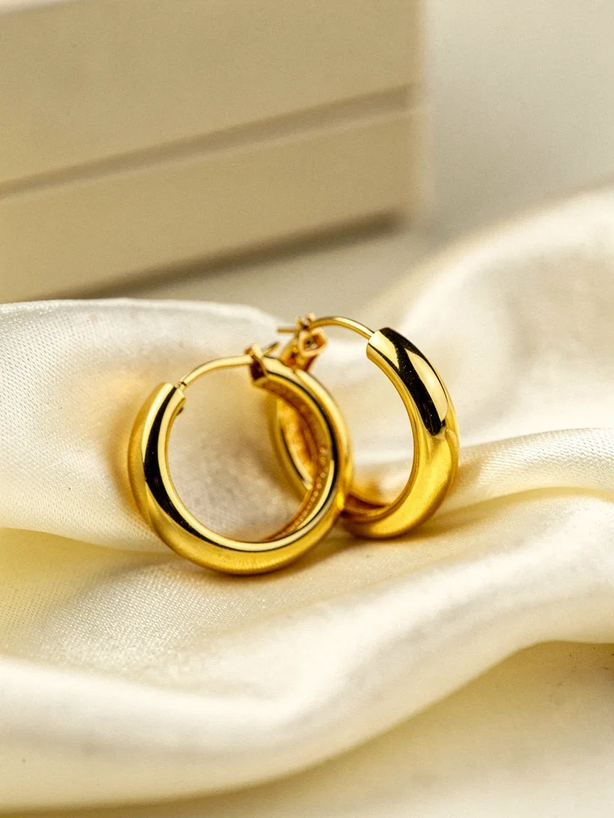 AI-generated jewelry catalog macro of gold hoop earrings on ivory silk, made on FluxoKit
