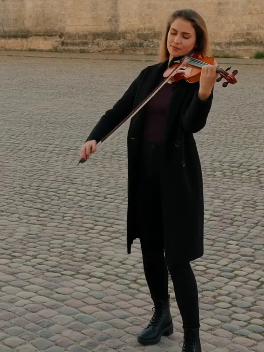 Violinist mid-phrase on the cobblestone plaza, beat frame from a Hailuo 2.3 clip on FluxoKit