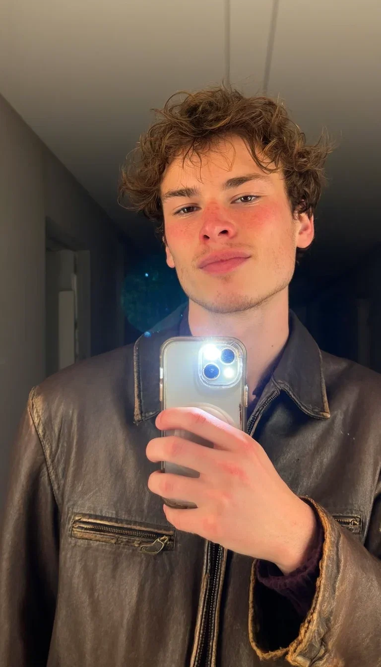 Authentic mirror selfie of a man in a vintage leather jacket in a dim hallway, generated with Higgsfield Soul on FluxoKit