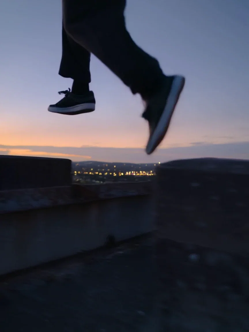 City lights bokeh behind the rooftop ledge, beat frame from a Kling 2.6 clip on FluxoKit