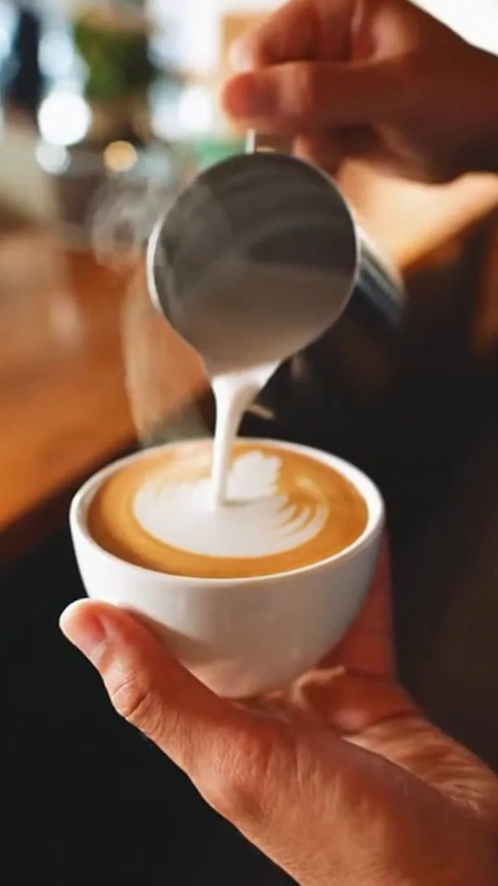 Close-up of a barista pouring latte art with steam rising and ambient cafe sound, generated with Sora 2 on FluxoKit