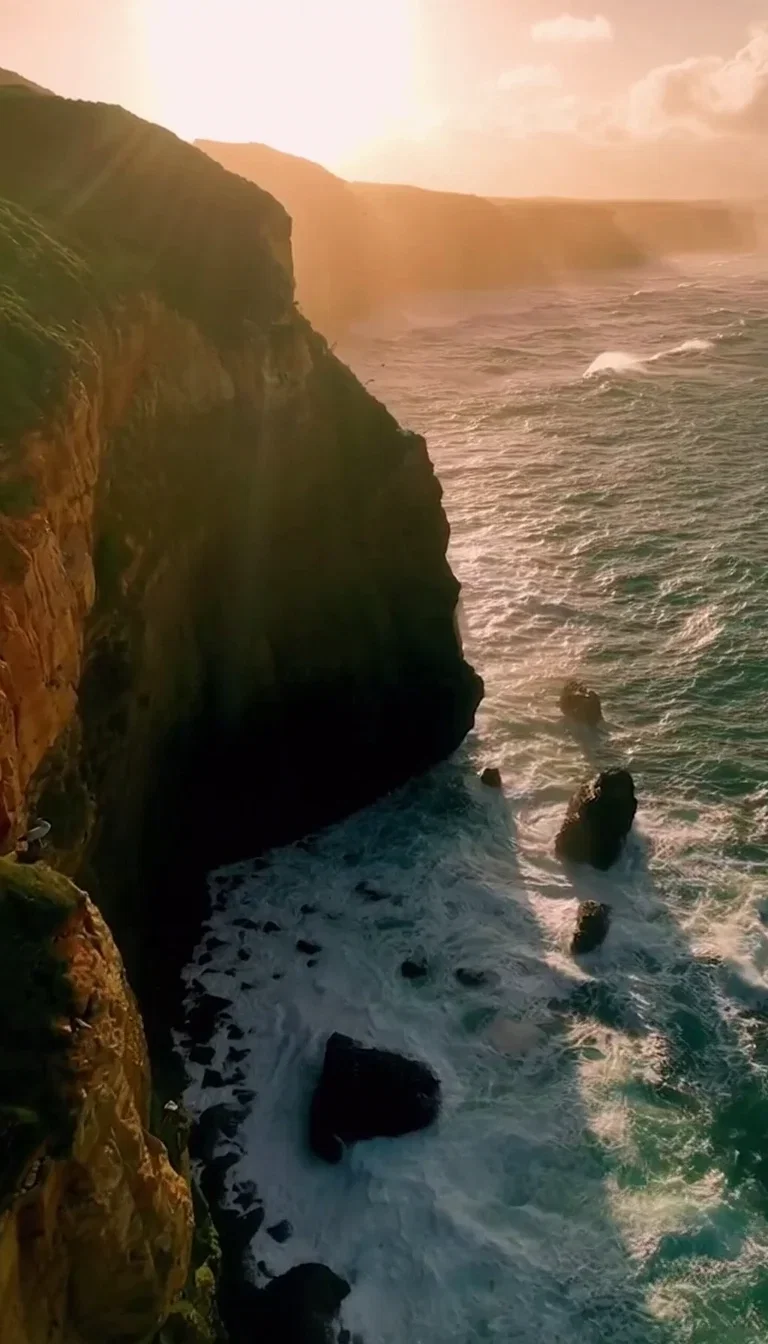 Frame from a Sora 2 Pro aerial clip of a golden-hour sea cliff, generated on FluxoKit